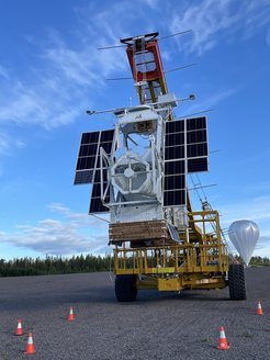 Das Observatorium Sunrise III kurz vor dem Start am Kranfahrzeug Hercules. Der riesige Ballon rechts im Hintergrund ist bereits zum Teil mit Helium befüllt. Er trägt während des Flugs eine Last von fast drei Tonnen
