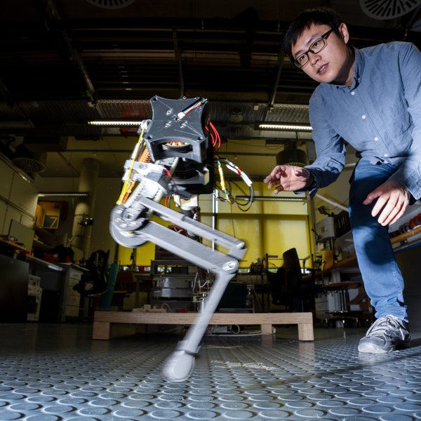 A man witz casual clothes watches a two-legged robot.