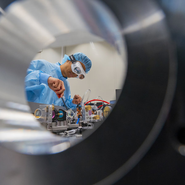 A man wearing protective clothing and goggles is working in the laboratory.